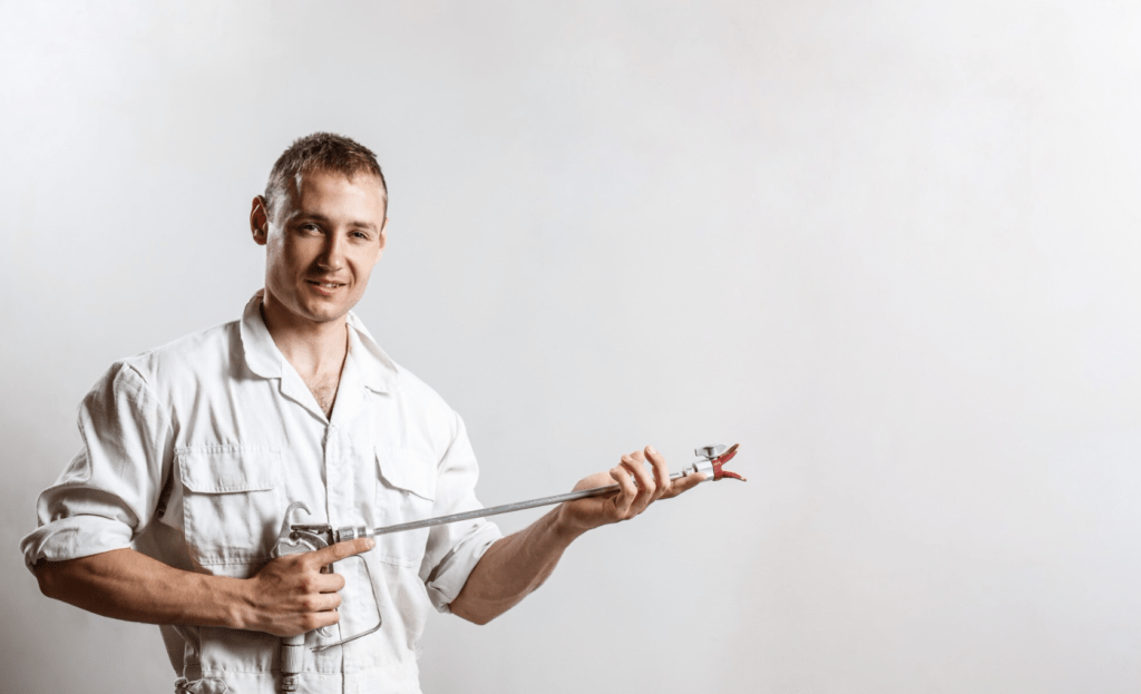 worker excited to get more painting jobs, holding a spray gun 