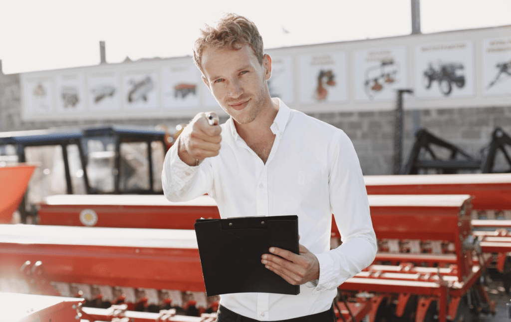 business consultant pointing at you with farm equipment in the back ground 